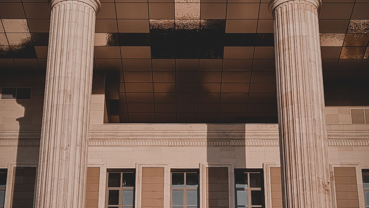 Columnas en la entrada de un juzgado. ¿Por qué revisar la Rama Judicial a mano ya no es suficiente para vigilar tus casos? — Compuasociados.