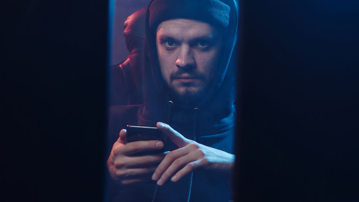 Persona en la penumbra usando un teléfono, símbolo de riesgo de manipulación de datos. Una actuación que aparece, cambia o desaparece: cómo blindar tu expediente — Compuasociados.